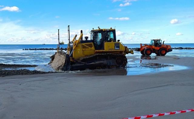 Żółta spycharka pracuje na plaży nad morzem