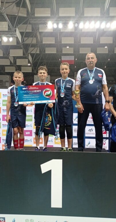 Młodzi sportowcy i&nbsp;trener na&nbsp;podium z&nbsp;trofeami