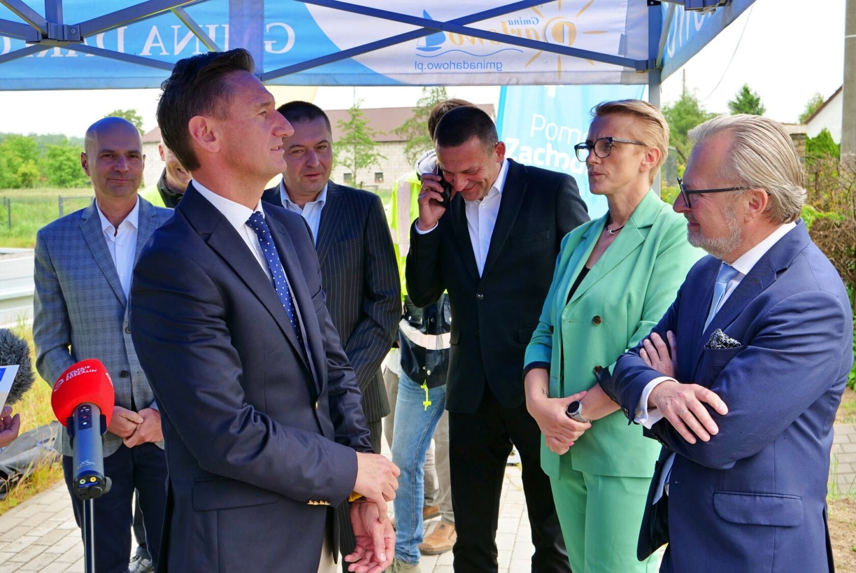 503998961_1117108203776236_6037587435088704260_n Grupa osób w garniturach dyskutuje na zewnątrz