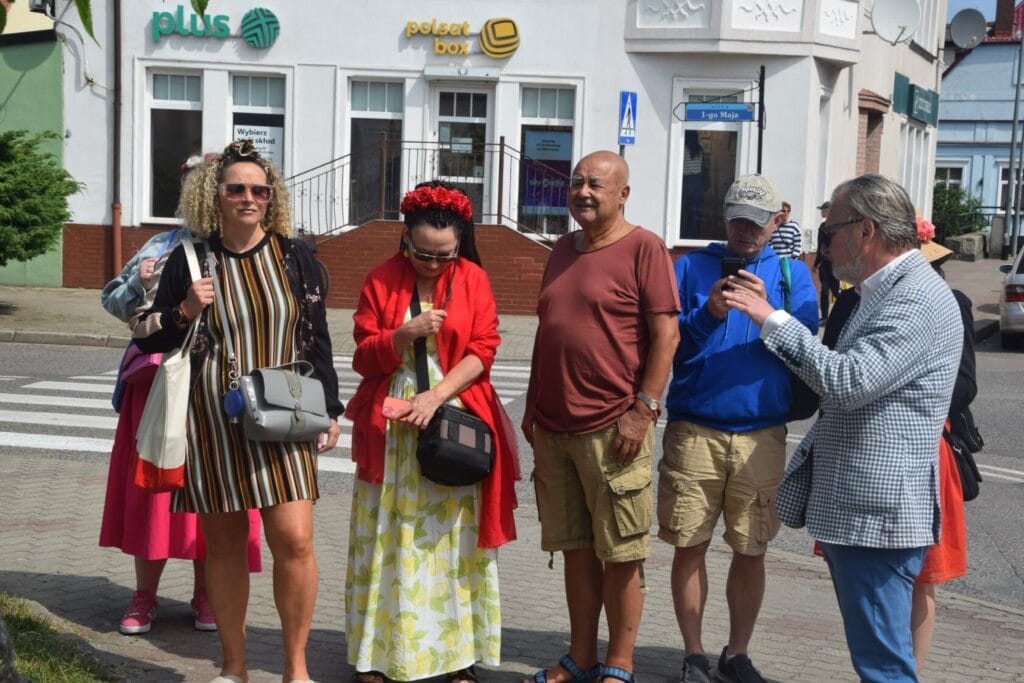 Grupa ludzi idąca przez miasto przy słonecznym dniu