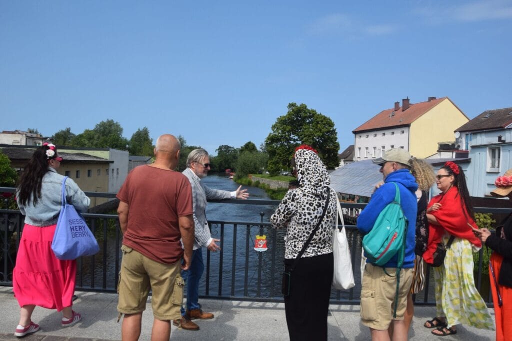 Ludzie rozmawiają na moście nad rzeką w słoneczny dzień