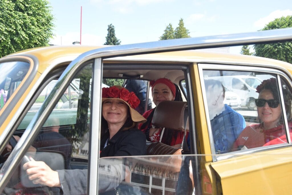 Kobiety w czerwonych nakryciach głowy w żółtym samochodzie