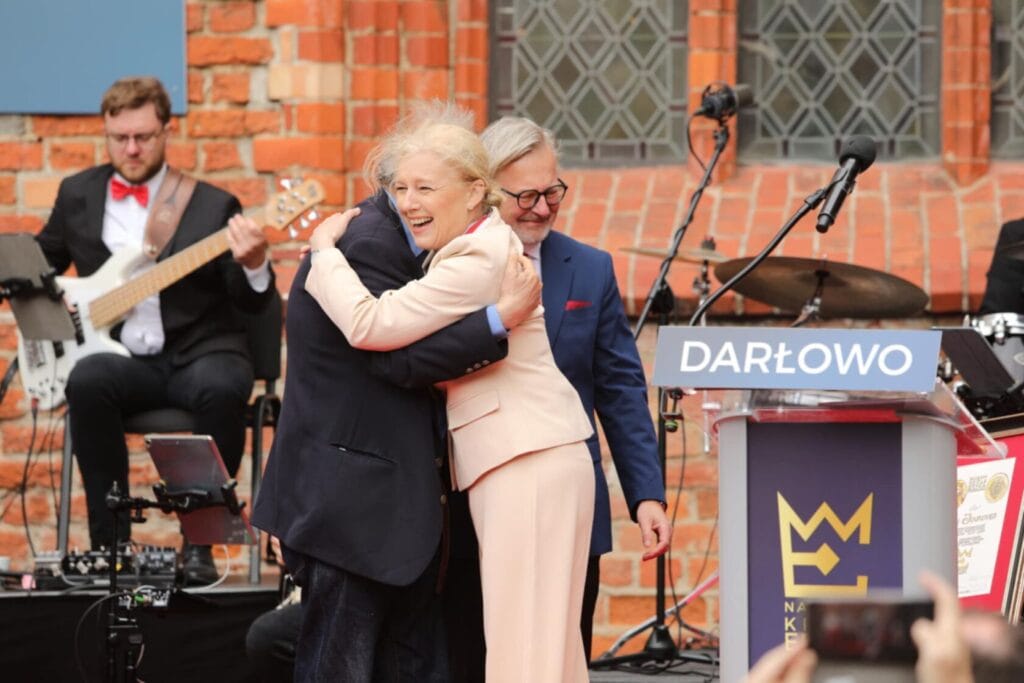Uśmiechnięte osoby przytulają się na scenie w Darłowie
