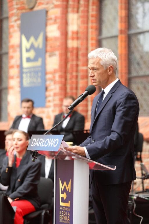 Starszy mężczyzna przemawia na podium w Darłowie.