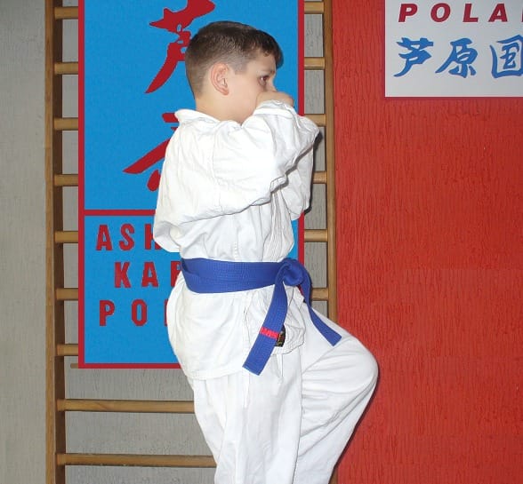 Chłopiec w białym karategi i niebieskim pasie pozujący