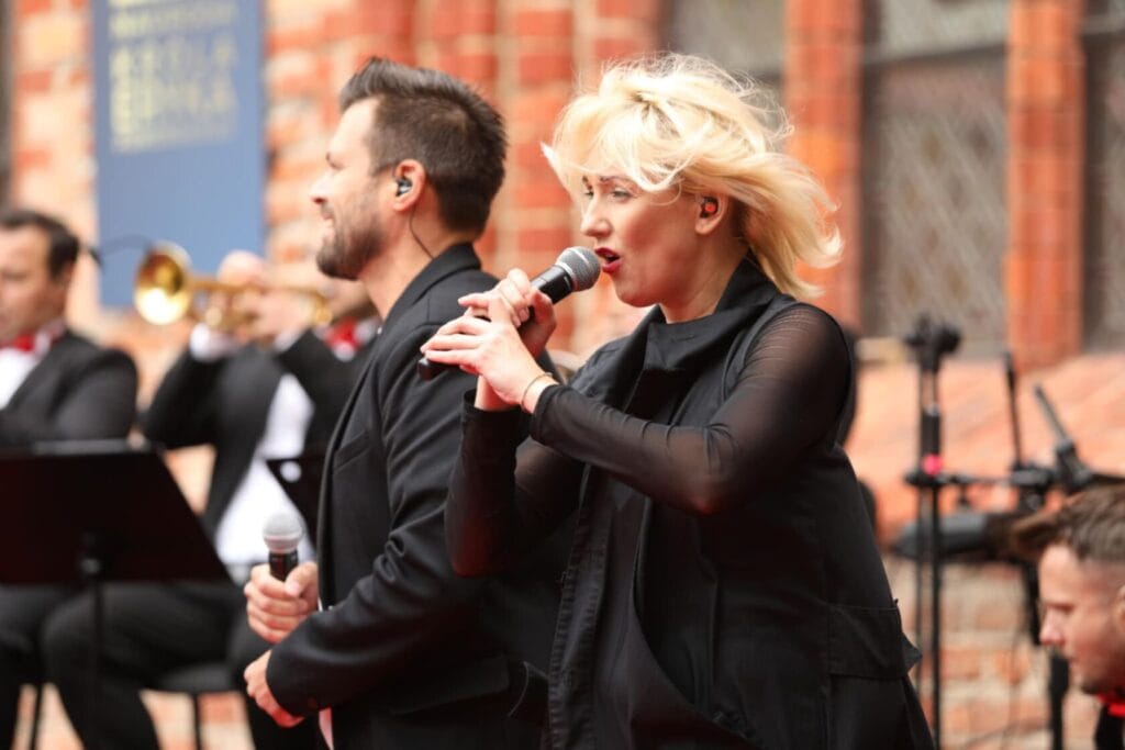 Kobieta śpiewa na żywo z mężczyzną i orkiestrą
