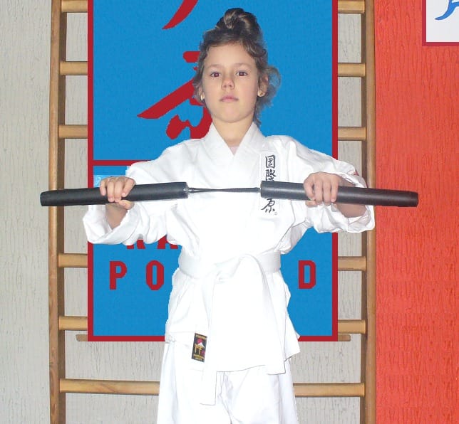 Dziewczynka w karate-gi trzyma bo w dojo