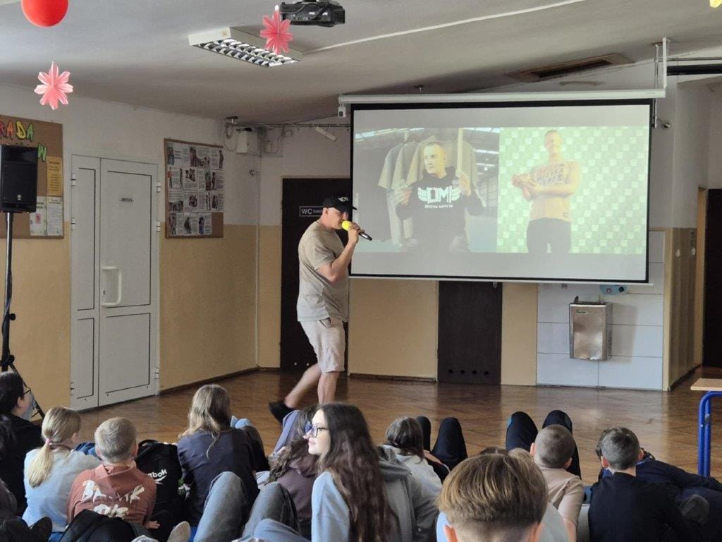 Młodzież ogląda prezentację szkolną z prelegentem i ekranem