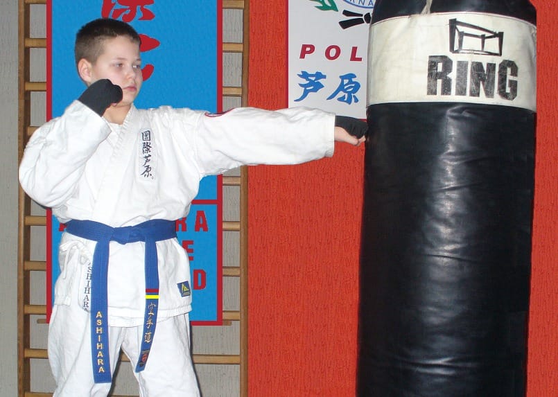 Młody karateka trenuje ciosy na worku treningowym