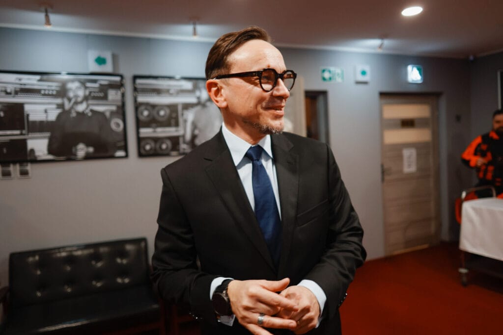 Mężczyzna w garniturze uśmiecha się w eleganckim pomieszczeniu