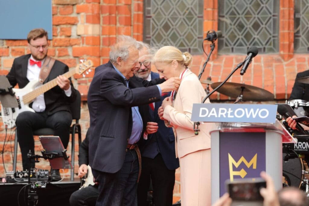 Starszy mężczyzna wręcza odznaczenie kobiecie na scenie