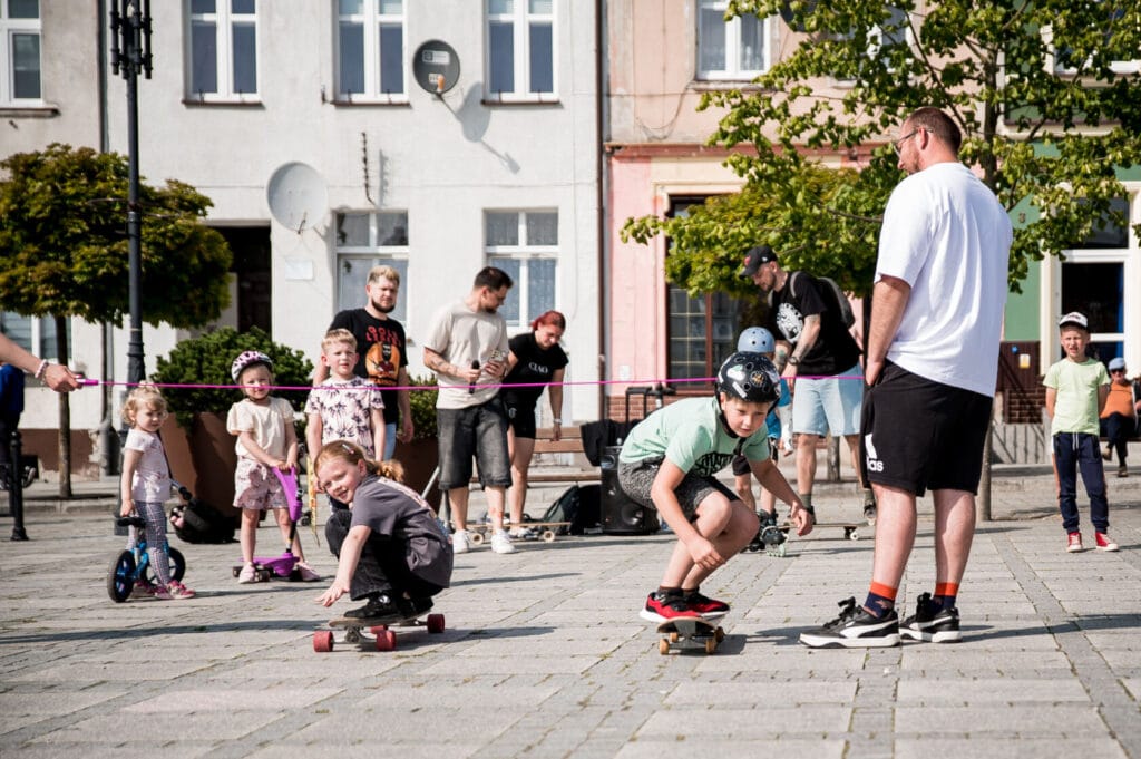 Dzieci uczą się jazdy na deskorolce na miejskim placu