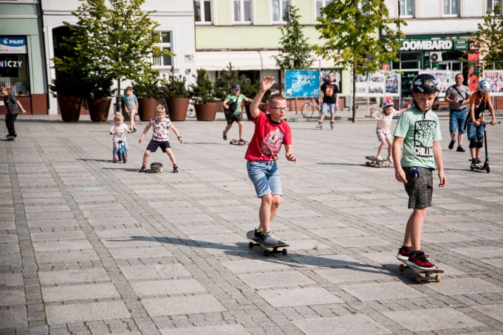 Dzieci bawiące się na deskorolkach na miejskim placu