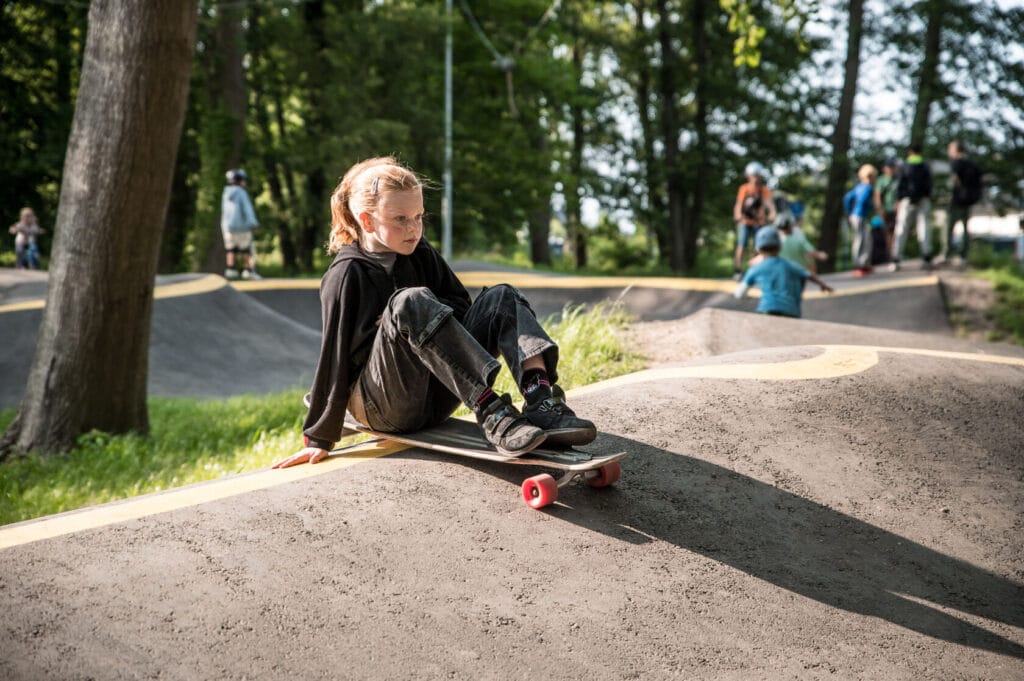 Dziecko siedzi na deskorolce w parku skatepark