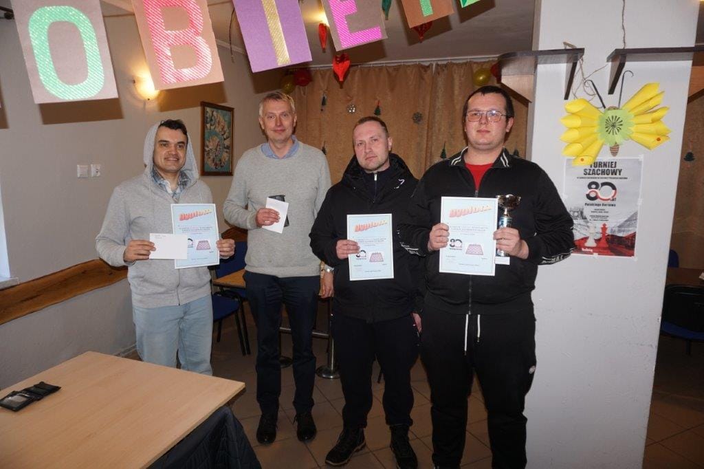 Czterech mężczyzn z dyplomami w pomieszczeniu z dekoracjami