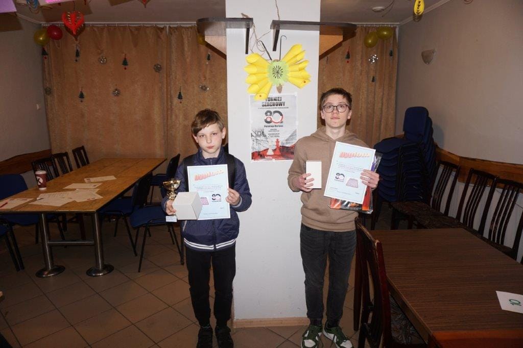 Dwóch chłopców z dyplomami i pucharem w sali