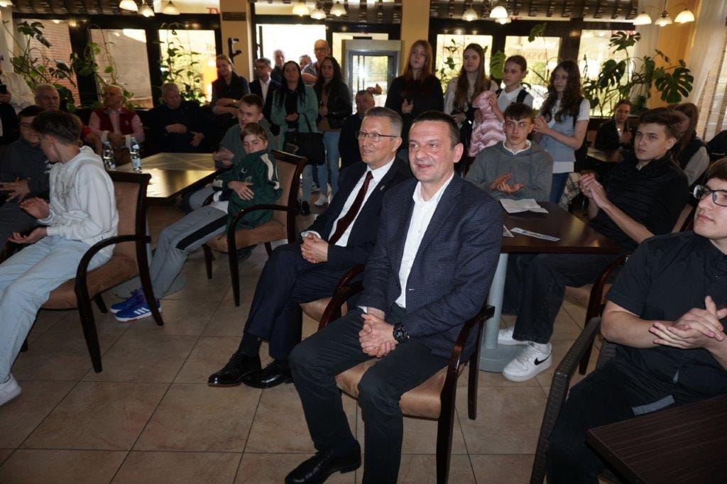 Grupa osób siedzących w przestronnym pomieszczeniu