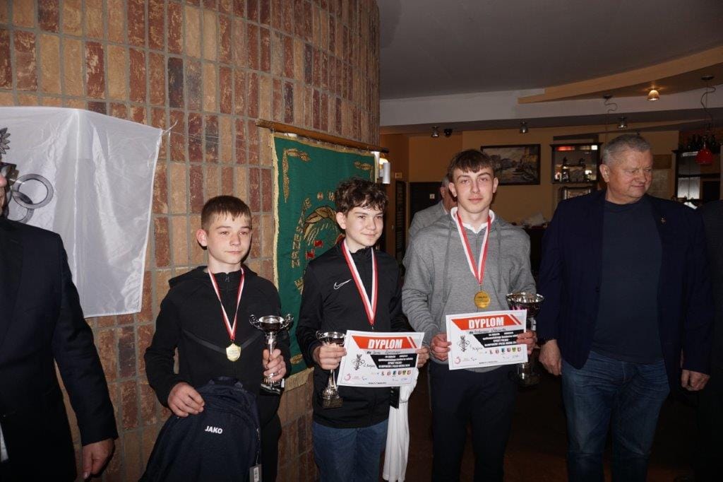 Trzej młodzi sportowcy z medalami i pucharami.