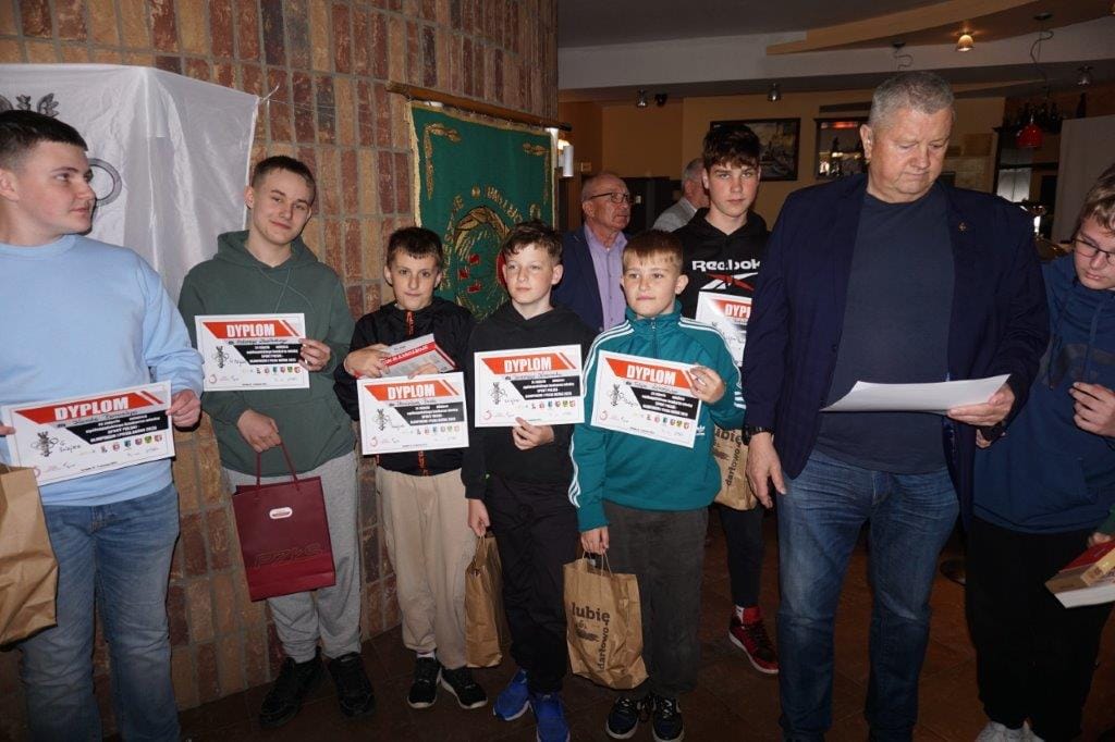 Grupa chłopców z dyplomami i mężczyzna czytający dokument