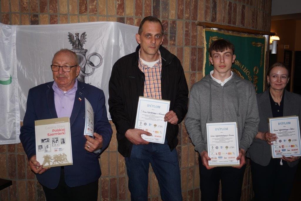 Cztery osoby z dyplomami przy ceremonii nagrodzenia