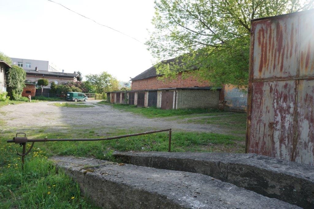 Opuszczony teren ze zdewastowanymi budynkami i zielenią