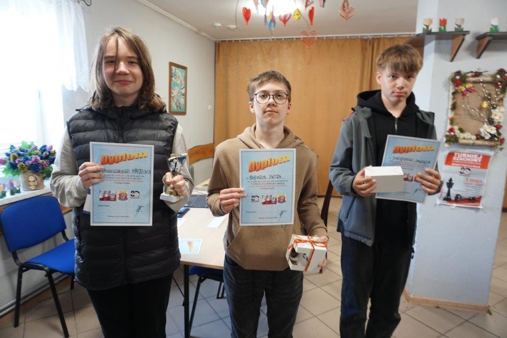 Trzej młodzi ludzie z dyplomami i nagrodami w rękach