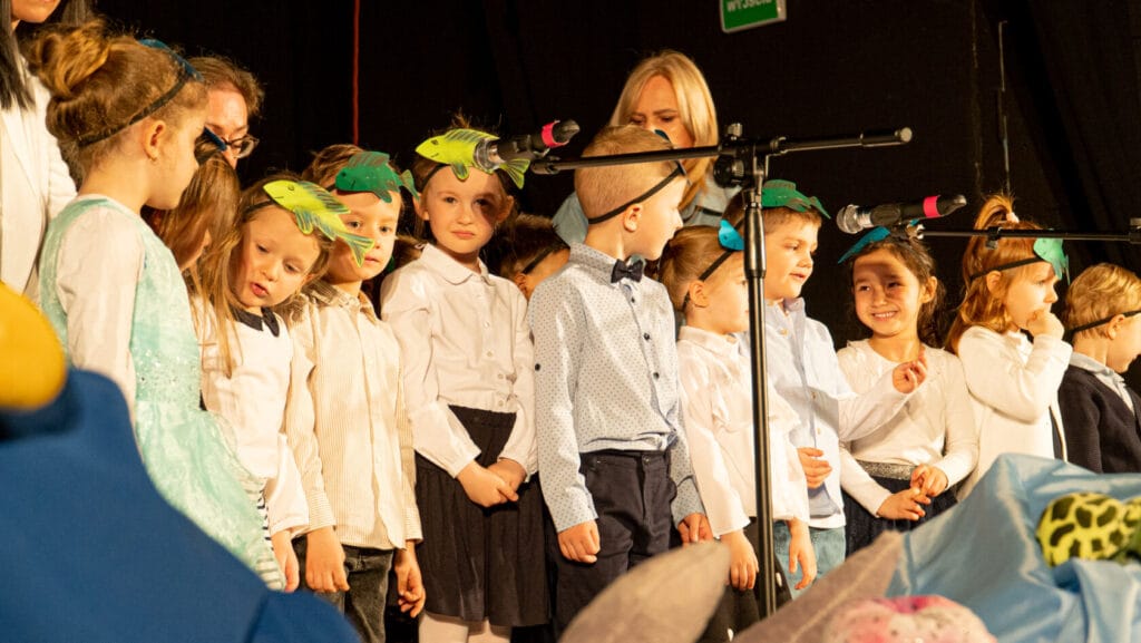 Dzieci w eleganckich ubraniach śpiewają podczas szkolnego występu