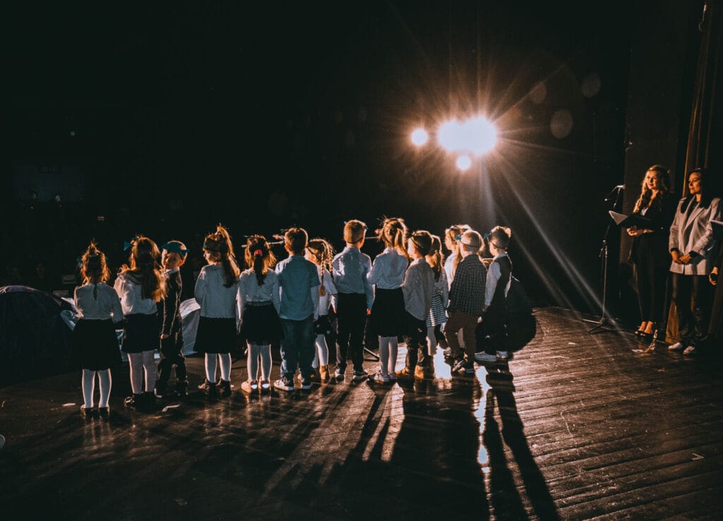 Dzieci na scenie w szkolnym przedstawieniu.