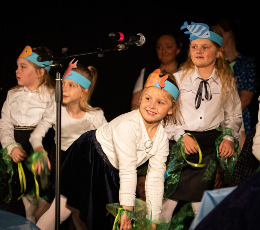 Dzieci w kostiumach występują na scenie szkolnej