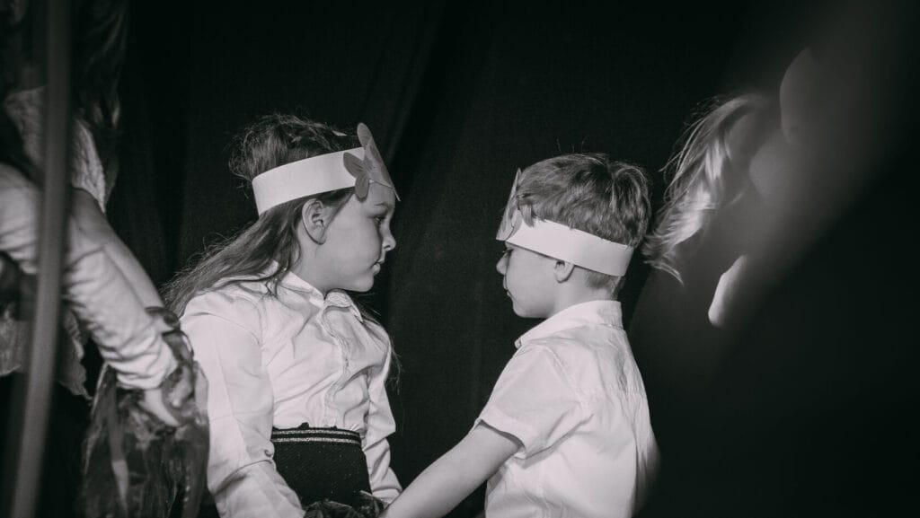 Dzieci w kostiumach z kartonowymi koronami na scenie