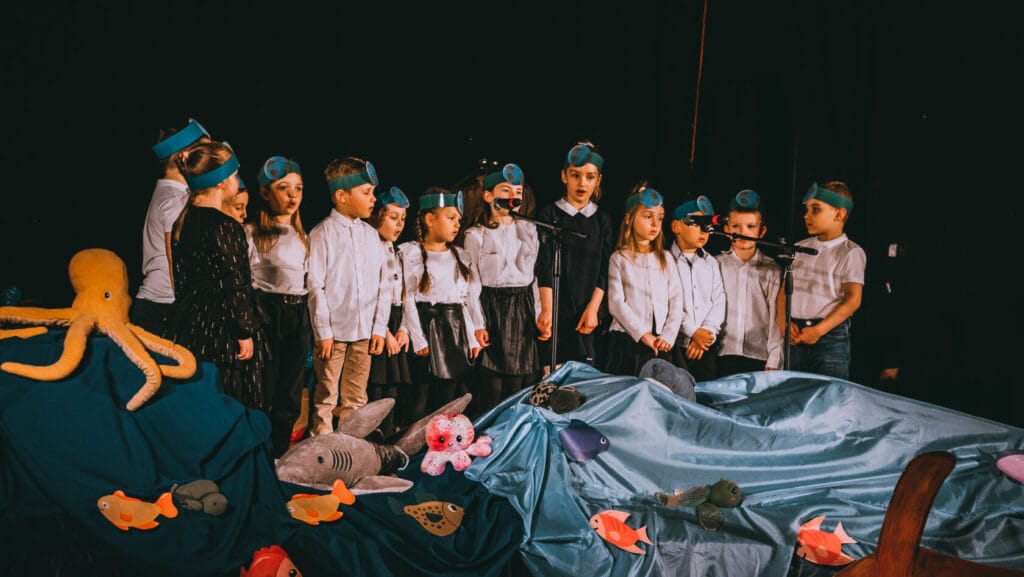 Dzieci występują w szkolnym przedstawieniu o tematyce morskiej