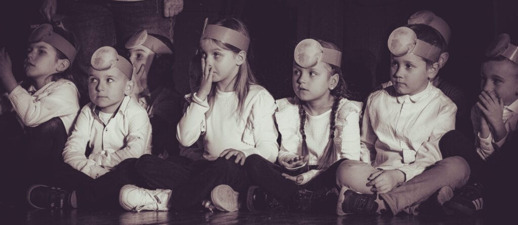 Dzieci w opaskach z globusami podczas szkolnego występu