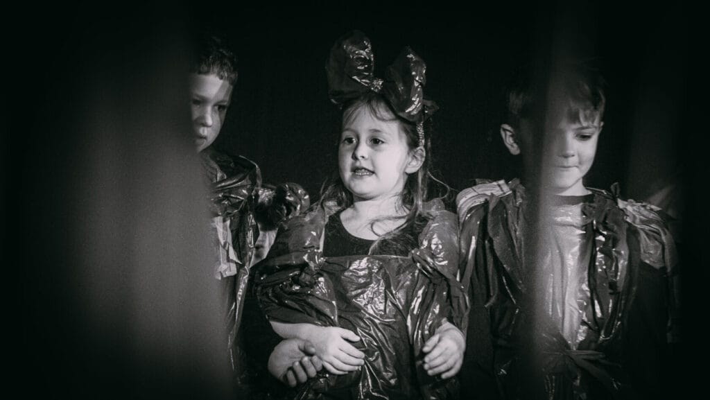Dzieci w czarno-białych strojach foliowych na scenie