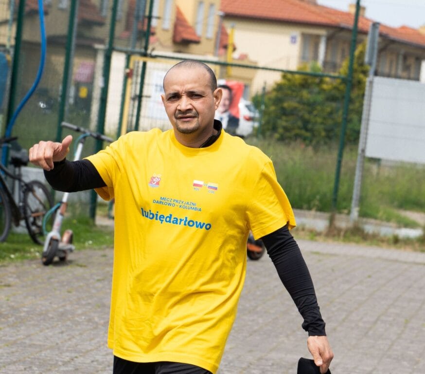 Mężczyzna w żółtej koszulce biega na boisku