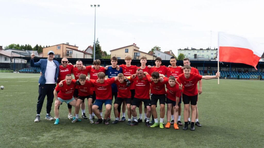 Młoda drużyna piłkarska Polska z flagą na stadionie