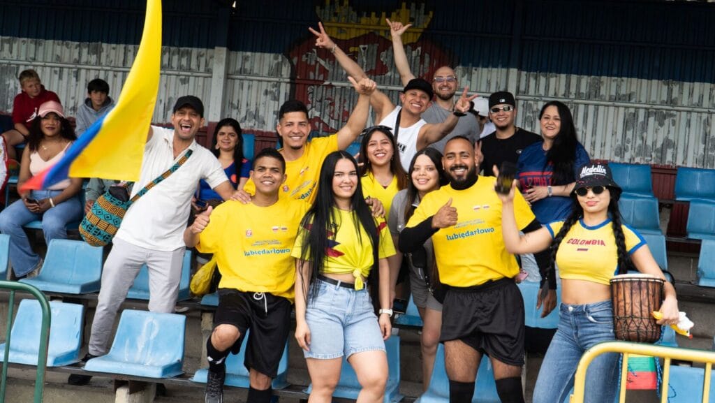 Radosni kibice w żółtych koszulkach na stadionie.