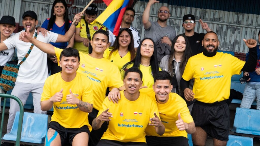 Grupa uśmiechniętych kibiców w żółtych koszulkach