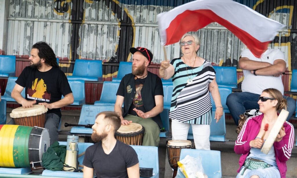 Grupa ludzi z bębnami i flagą na trybunach