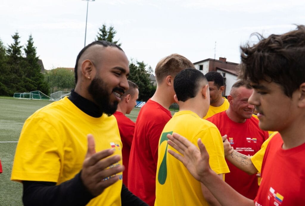 Młodzi ludzie w żółtych koszulkach rozmawiają na boisku