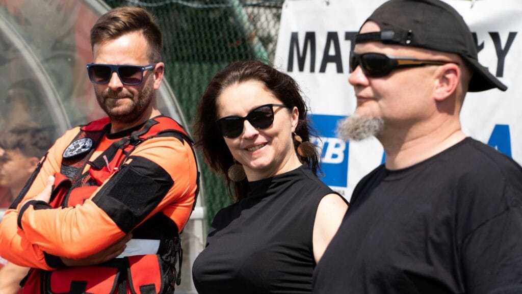 Trzech ludzi na zewnątrz, uśmiechnięci, stylowa odzież