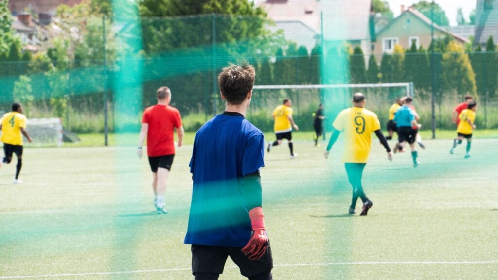 Bramkarz obserwuje mecz piłki nożnej na boisku.