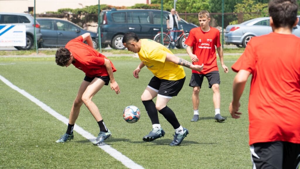 Mężczyźni grający w piłkę nożną na trawiastym boisku