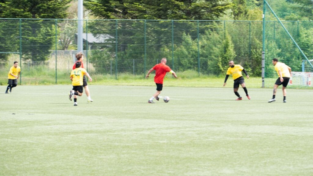 Piłkarze grają na zielonym boisku.