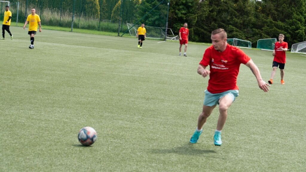 Mężczyzna biegnie za piłką na boisku piłkarskim