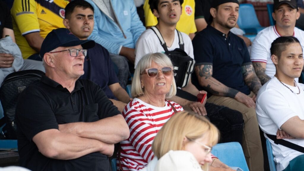 Starsze małżeństwo ogląda mecz w tłumie na stadionie.