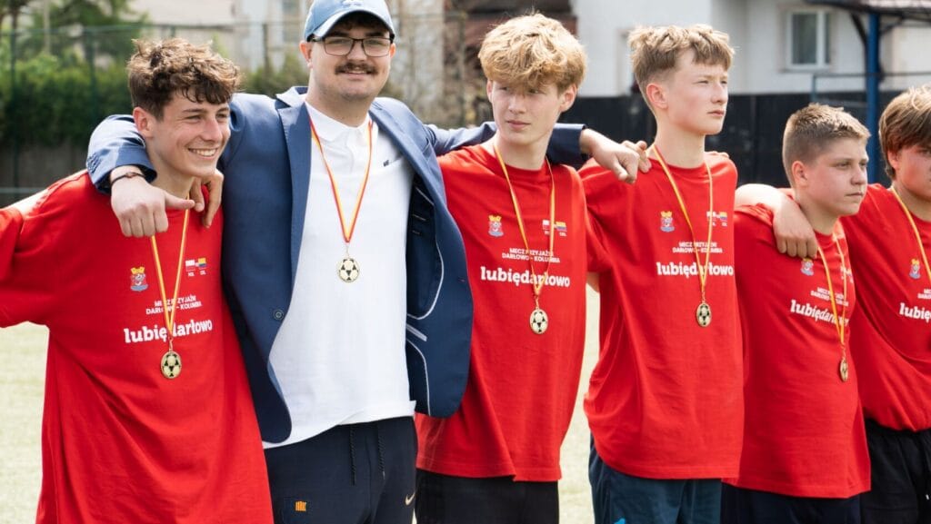 Młodzi sportowcy z trenerem świętują zwycięstwo na boisku