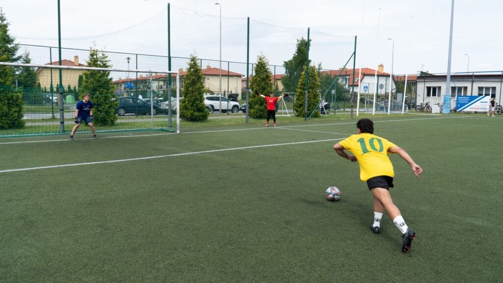 Piłkarze grają na boisku ze sztuczną trawą