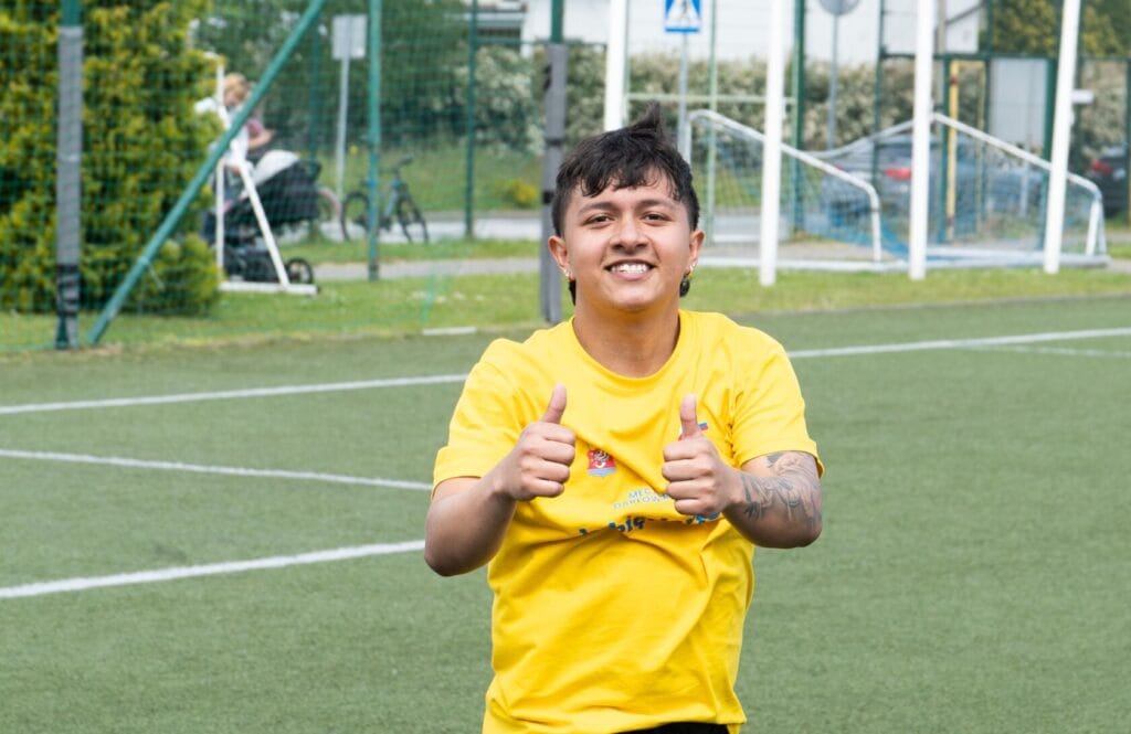 Młody mężczyzna pokazuje kciuki na boisku