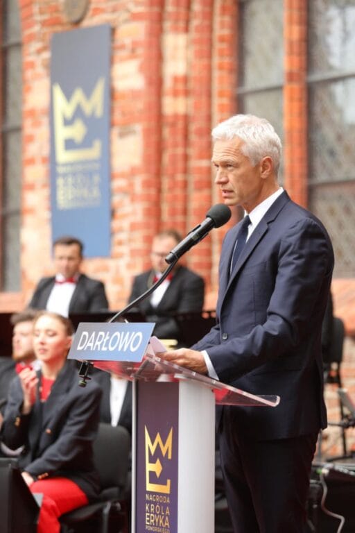 Starszy mężczyzna przemawia na podium w Darłowie