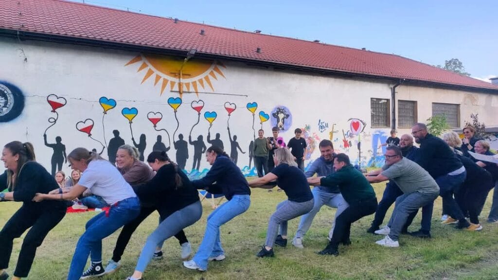 Grupa ludzi bawi się w przeciąganie liny na zewnątrz